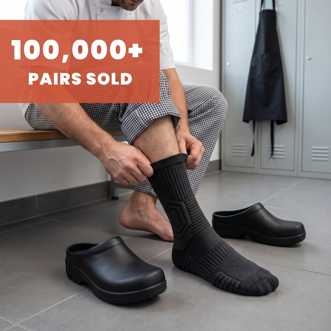 Cook on a changing room bench pulling on a black Shift Sock, black kitchen shoes beside him, 100,000+ pairs sold.