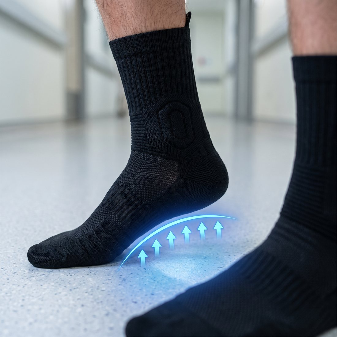 Close-up of a foot in a black Shift Sock with a blue glow and arrows lifting the arch, on a hospital floor.