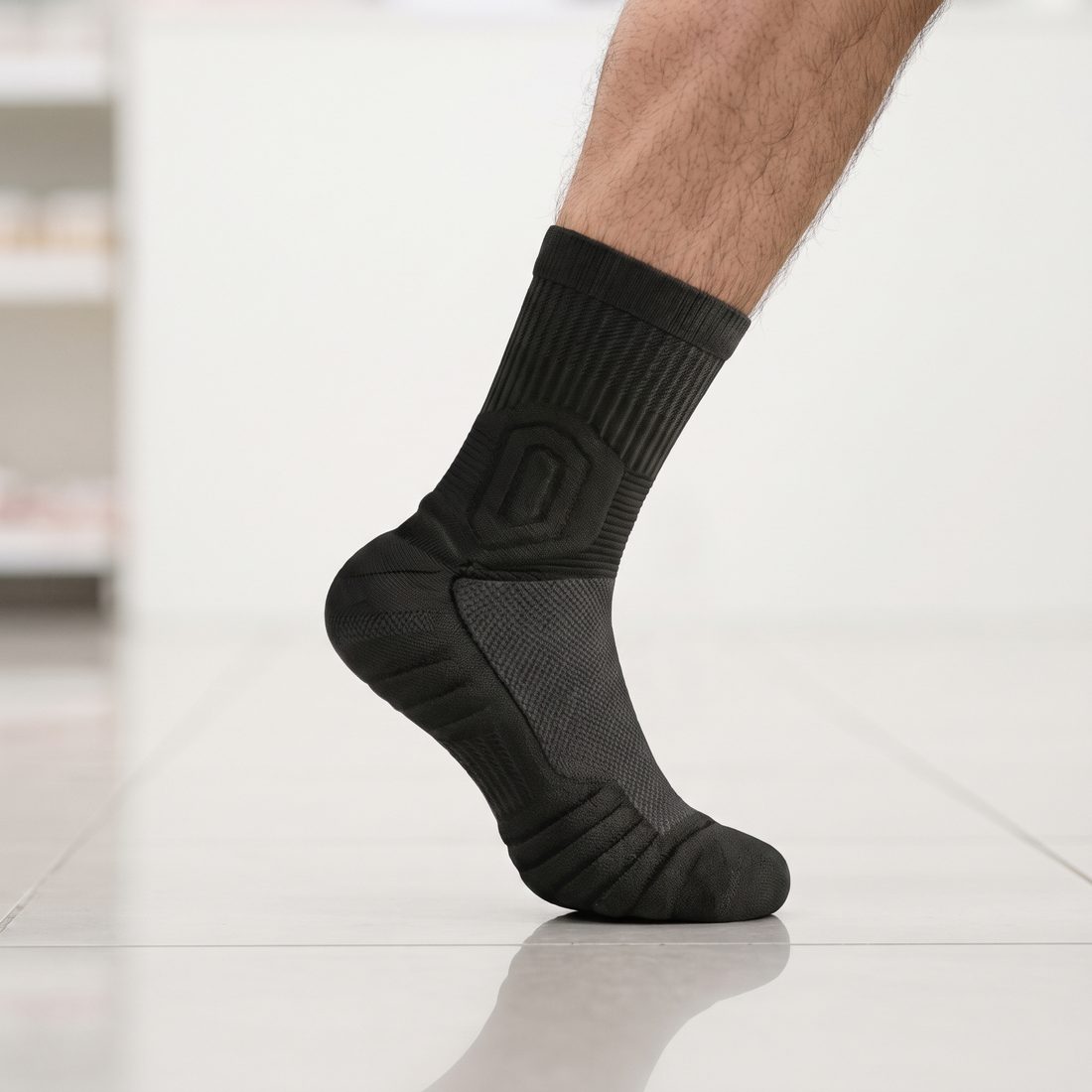 Man's foot on tiptoe in a black Shift Sock on a pale store floor.