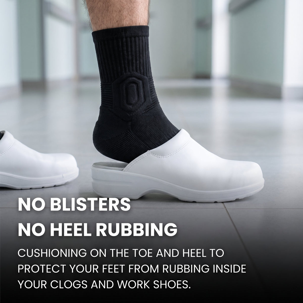 Man's foot in a black Shift Sock sliding into a white hospital clog on a tiled floor.